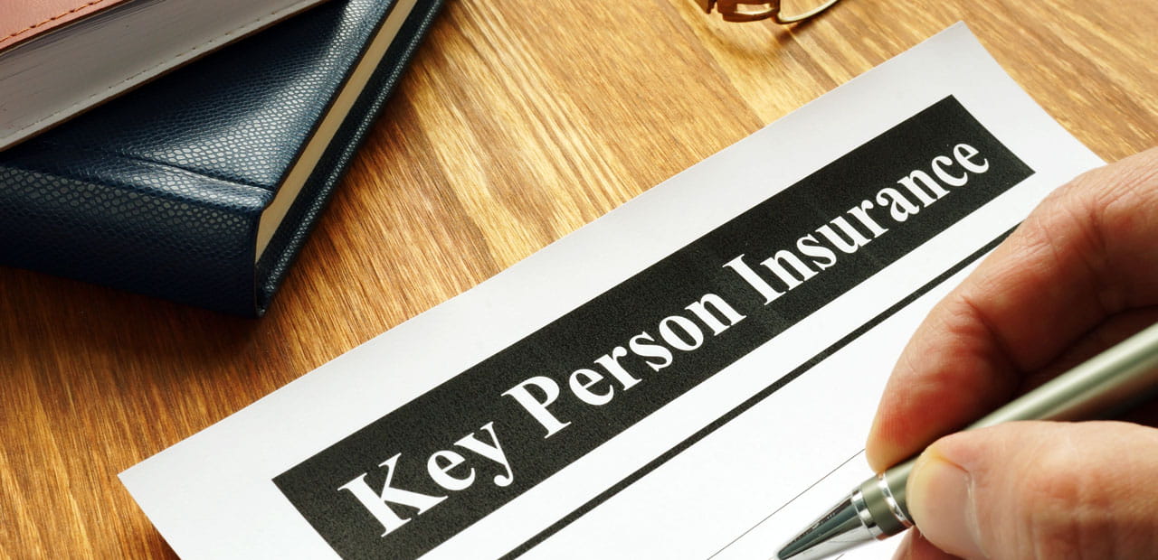 A person filling out a form titled "Key Person Insurance".