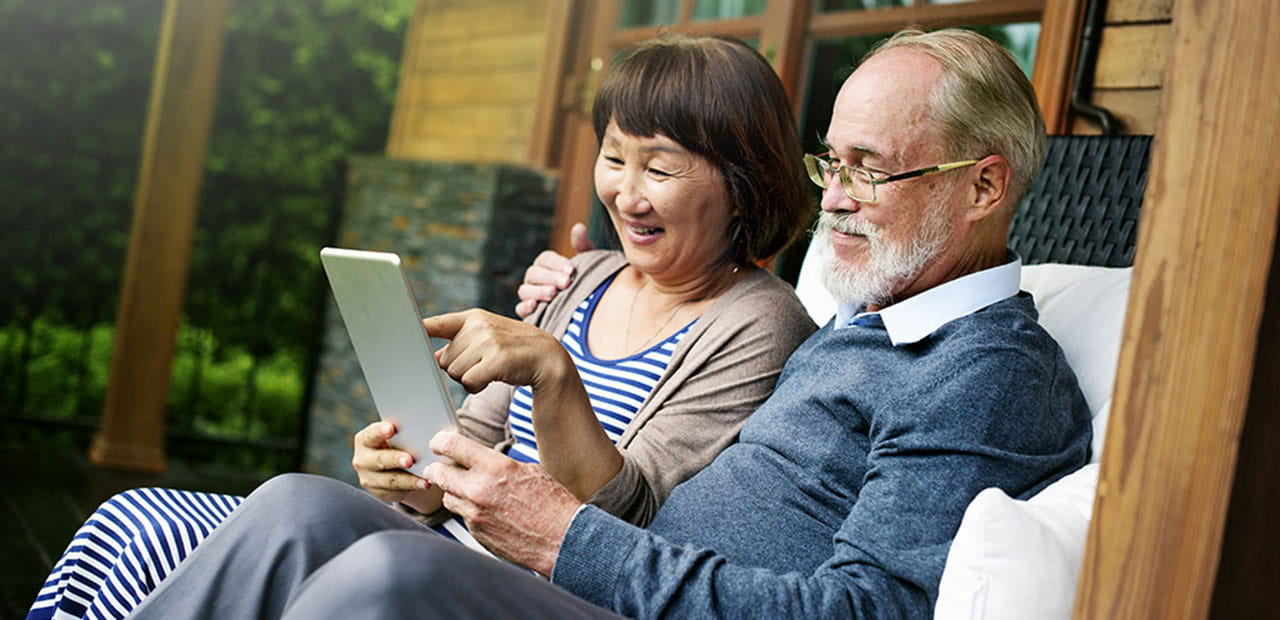 An elderly couple watching something on a tablet